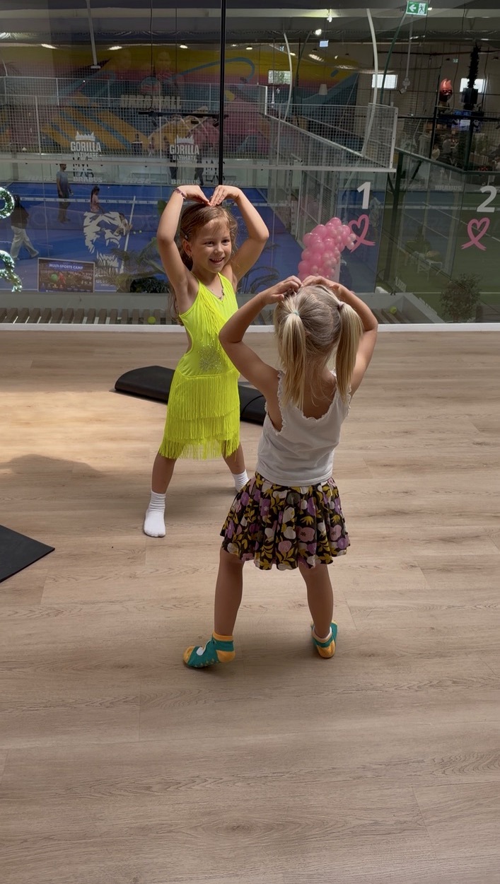 Two little girls dancing together in class